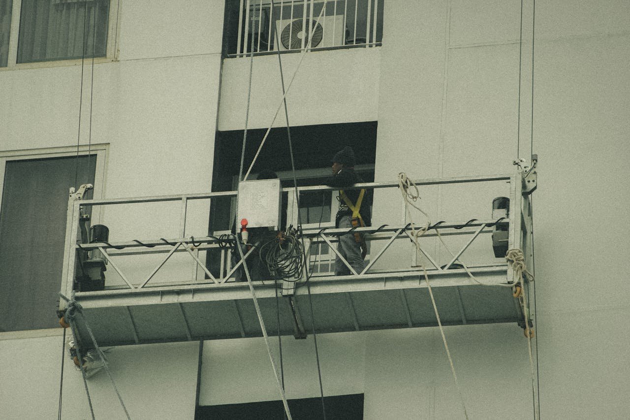 A worker on a suspended scaffold is repairing a building facade.